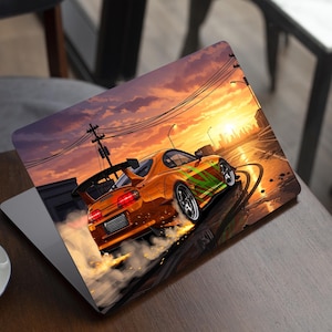 May include: Laptop with a vibrant orange car graphic, featuring green accents, drifting on a wet road at sunset. The design showcases a dynamic racing scene, with smoke and a cityscape in the background.