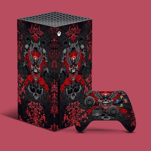 May include: Black and red gaming console skin and controller featuring a skull and floral design. The console skin has a repeating pattern of skulls, roses, and ornate scrollwork. The controller has a matching design.