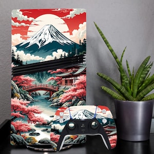 以下が含まれることがあります： 日本の風景デザインが施されたPlayStation 5コンソールスキンとコントローラー。アートワークには富士山、赤い太陽、桜、伝統的な橋が含まれています。コントローラーは黒いベースに白いボタンが付いています。