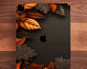May include: A black tablet with a fall-themed leaf design. The leaves are in shades of orange, brown, and gray, arranged around the edges of the tablet. The Apple logo is visible on the back.