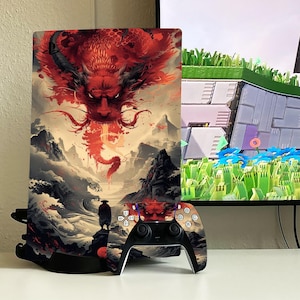 May include: A black and white video game console with a red, white, and black dragon design. The console is sitting on a black stand. A black and white video game controller with a red, white, and black dragon design is sitting in front of the console.