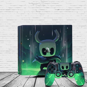 May include: A green and black PlayStation 4 console with a custom skin featuring a character from the video game Hollow Knight. The console is sitting on a white brick wall. A matching green and black PlayStation 4 controller is in the foreground.