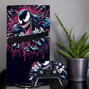 以下が含まれることがあります： 黒いゲーム機とコントローラーのスキン。ヴェノムのデザインで、青、ピンク、白の色合いでヴェノムの詳細なイラストが描かれています。コントローラーには黒と白のアクセントがあります。