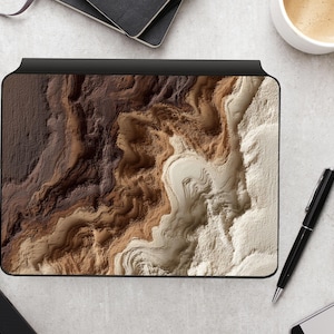 Könnte beinhalten: Eine schwarze Laptop-Hülle mit einem strukturierten, abstrakten Design in Braun-, Beige- und Weißtönen. Die Hülle hat einen schwarzen Rand und ein einzigartiges, geschichtetes Aussehen. Das Design ähnelt einer topografischen Karte oder einem Gesteinsquerschnitt.