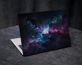 May include: A laptop computer with a dark blue and purple galaxy-themed design on the lid. The design features swirling clouds of gas and dust, with scattered stars.