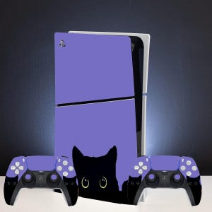 May include: A PlayStation 5 console with a purple faceplate featuring a black cat design, and two matching purple and black controllers. The controllers have white buttons and a PlayStation logo.