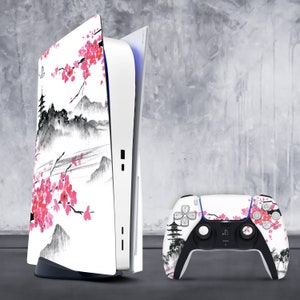 Könnte beinhalten: Eine weiße PlayStation 5 Konsole mit einer benutzerdefinierten Haut, die ein japanisch inspiriertes Design mit Kirschblüten und einer Berglandschaft zeigt. Die Konsole steht neben einem passenden weißen PlayStation 5 Controller mit dem gleichen Design.