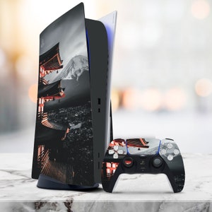 May include: A black and white PlayStation 5 console with a custom skin featuring a Japanese temple and mountain landscape. The console is next to a matching black and white PlayStation 5 controller.