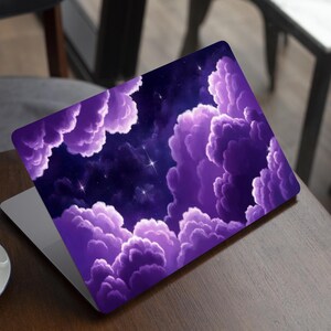 Può includere: Una skin per laptop con un vivace design del cielo notturno, caratterizzato da soffici nuvole viola e stelle luminose sparse. La grafica copre l'intero coperchio esterno del laptop, mostrando un tema celeste con un forte contrasto.