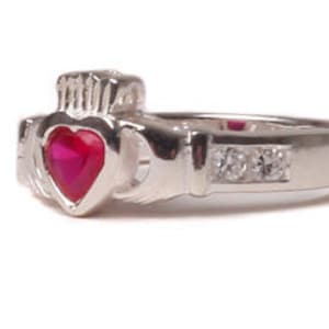 May include: A silver Celtic Claddagh ring with a red heart-shaped gemstone and clear cubic zirconia stones on the band.