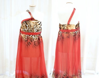 Puede incluir: Un vestido maxi rojo con un diseño de un solo hombro y un estampado de leopardo. El vestido está hecho de una tela transparente y tiene una silueta fluida.