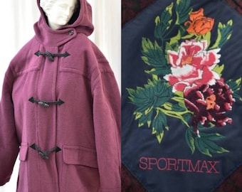 May include: A long, burgundy wool coat with a hood and toggle closures. The coat has a patch pocket on the front and a floral embroidered patch on the back that says "SPORTMAX".