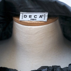 May include: A black satin blouse with a white label that reads "DECA&reg; PARIS MADE IN FRANCE".