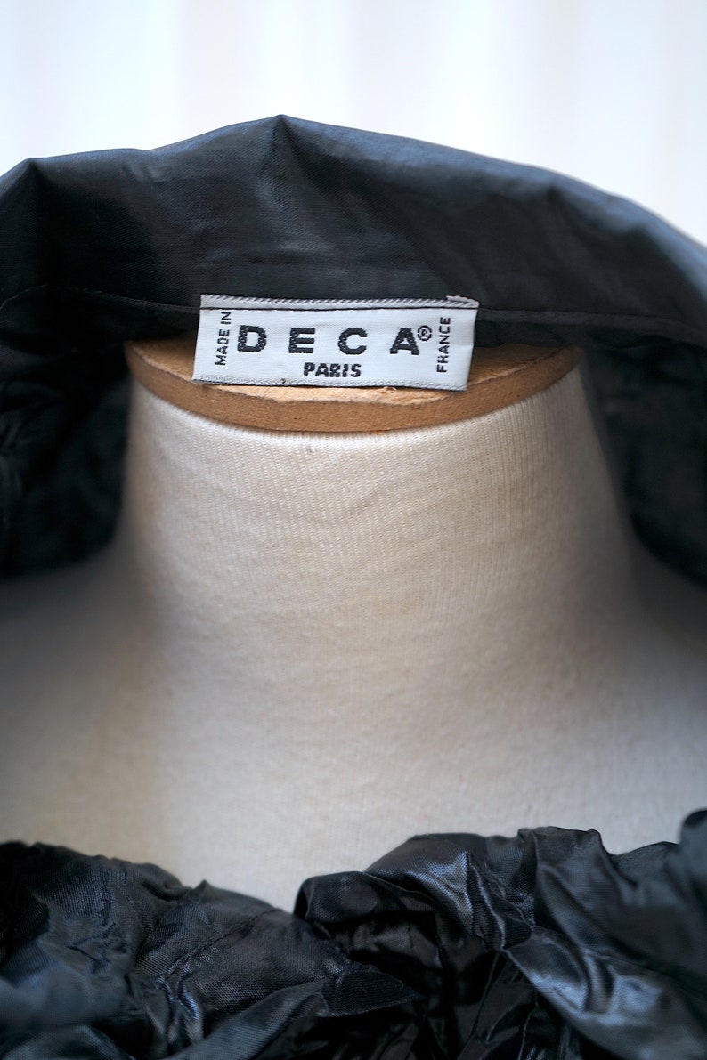 May include: A black satin blouse with a white label that reads "DECA&reg; PARIS MADE IN FRANCE".