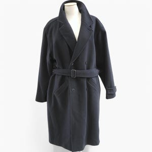 Peut inclure: Un long manteau en laine bleu foncé à double boutonnage, une ceinture et deux poches sur le devant.