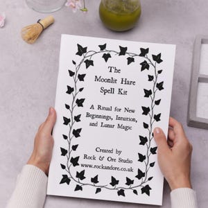 May include: A white card with black text and a decorative ivy border. The text reads "The Moonlit Hare Spell Kit: A Ritual for New Beginnings, Intuition, and Lunar Magic." Created by Rock & Ore Studio.