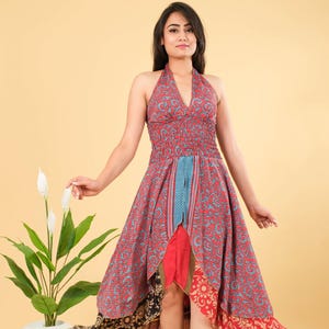 Puede incluir: Vestido halter con estampado de cachemira rojo y azul. El vestido presenta un corpiño fruncido y una falda asimétrica en capas con varias telas florales y estampadas. El vestido llega a la rodilla y es adecuado para climas cálidos.