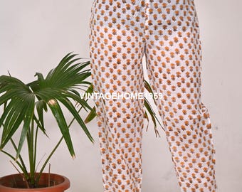 May include: White patterned trousers with an orange floral design and a drawstring waist. The text "VINTAGEHOME 1959" is visible on the trousers. These trousers are part of a casual clothing collection.