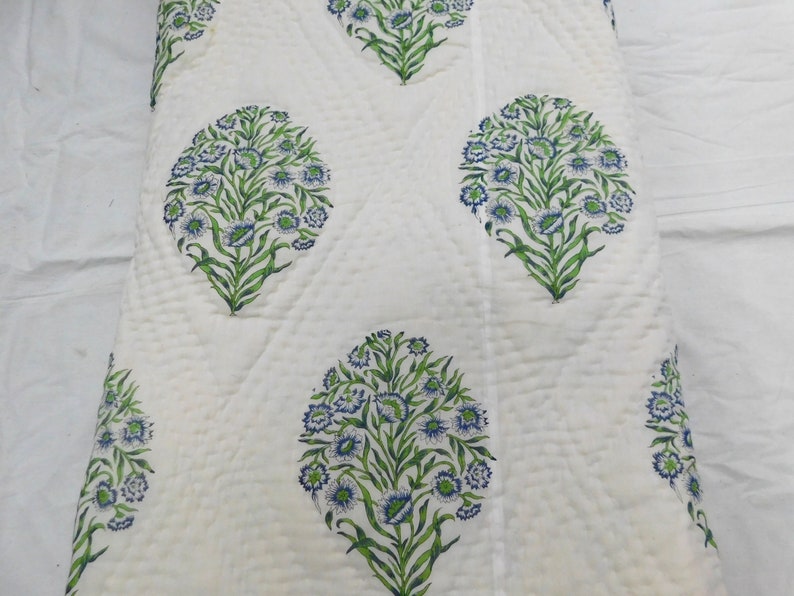 May include: White cotton quilt with a repeating pattern of blue and green floral designs. The quilt is quilted in a diamond pattern.