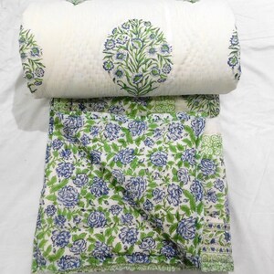 May include: White cotton quilt with a floral pattern in shades of green and blue. The quilt is folded in half and the top layer is patterned with a larger floral design.