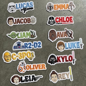 Puede incluir: Parches bordados con personajes y nombres de la franquicia Star Wars. Cada parche tiene un borde blanco e incluye retratos de personajes y nombres como "Lucas", "Leia" y "Luke".