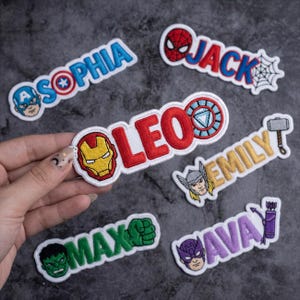 May include: Embroidered patches featuring superhero-themed designs and names. The patches include characters like Captain America, Spider-Man, Iron Man, Hulk, Thor, and Hawkeye, with names such as Sophia, Jack, Leo, Emily, Max, and Ava.