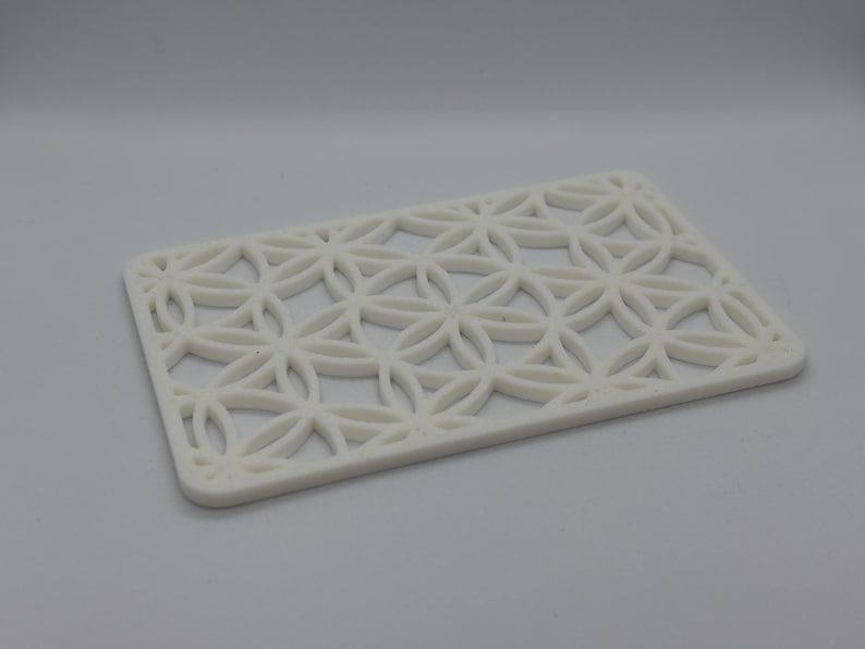 K&ouml;nnte beinhalten: Wei&szlig;es Kunststofftablett mit einem geometrischen Muster aus &uuml;berlappenden Kreisen und Blumenformen.