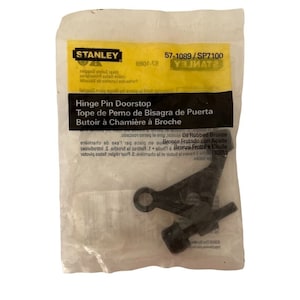 Könnte beinhalten: Ein schwarzer Türstopper aus Metall mit einer Schraube und einer kleinen Metallschlaufe. Die Verpackung ist gelb und schwarz und enthält die Produktnummer 57-1089/SP7100. Der Text "Hinge Pin Doorstop" ist auf der Verpackung in Englisch, Spanisch und Französisch aufgedruckt.