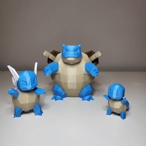 Peut inclure: Trois figurines Pokémon imprimées en 3D : Squirtle, Tortank et Carapuce. Les figurines sont en plastique brun clair avec des accents bleus. Les figurines sont en position debout.