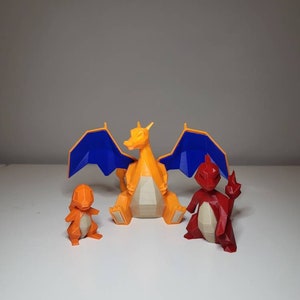 Peut inclure: Trois figurines Pokémon imprimées en 3D : un Charizard rouge, un Charmeleon orange et un Charmander jaune. Les figurines sont toutes de style low-poly.
