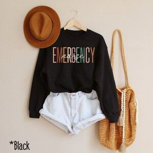 May include: Black sweatshirt with the text "EMERGENCY nurse" in colorful letters.