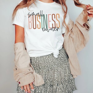 Puede incluir: Una camiseta blanca con el texto "small business owner" en rayas verticales de colores. El texto est&aacute; en un estilo de fuente moderno.