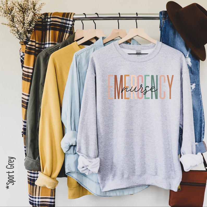 May include: A gray sweatshirt with the text "EMERGENCY nurse" in colorful letters. The letters are stacked vertically and the word "nurse" is written in cursive.