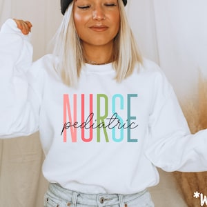 May include: White long-sleeved sweatshirt with the text "NURSE pediatric" in rainbow colors.