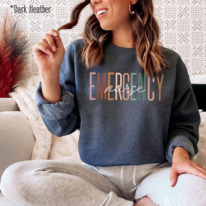 May include: Dark heather grey sweatshirt with the text "EMERGENCY nurse" in colorful letters.