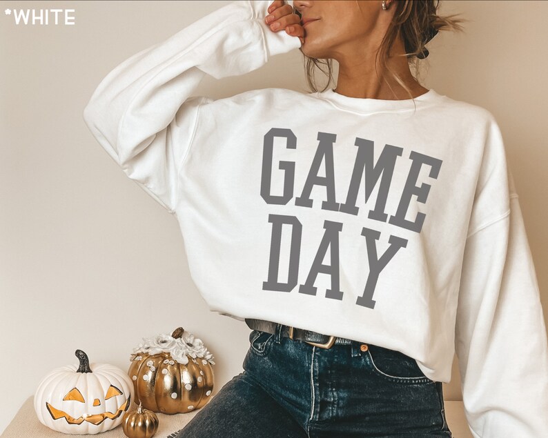 K&ouml;nnte beinhalten: Wei&szlig;er Pullover mit dem Text "GAME DAY" in grauen Buchstaben.
