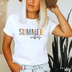 以下が含まれることがあります： レオパード柄のカラフルな文字で「SUMMER vibes」と書かれた白いTシャツ。