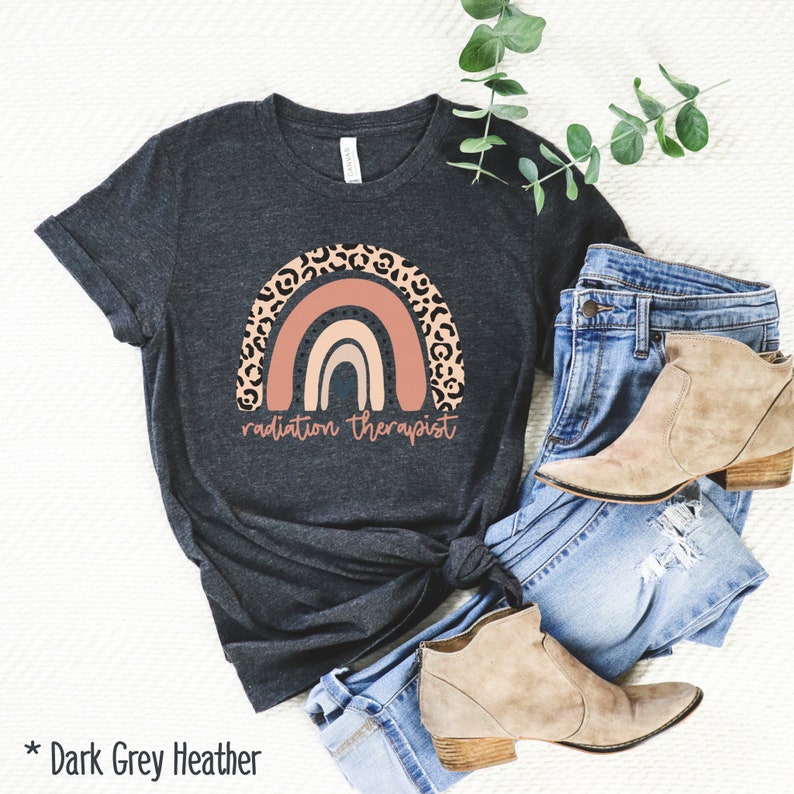 Puede incluir: Camiseta de color gris oscuro jaspeado con un dise&ntilde;o de arco&iacute;ris y el texto "radiation therapist". El arco&iacute;ris est&aacute; decorado con un estampado de leopardo.