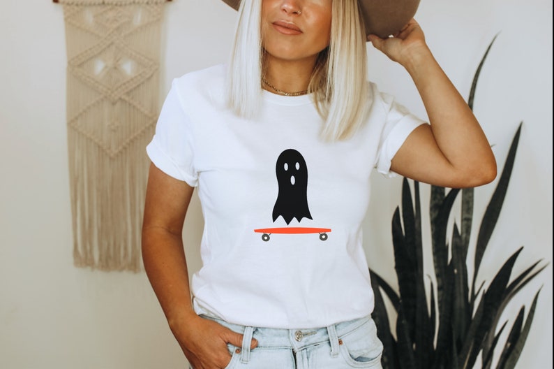 Peut inclure: T-shirt blanc avec un motif de fant&ocirc;me noir sur un skateboard rouge. Le fant&ocirc;me a trois trous pour les yeux. Le skateboard a des roues noires. Ce t-shirt d&eacute;contract&eacute; est adapt&eacute; au quotidien. Le design a un th&egrave;me d'Halloween.