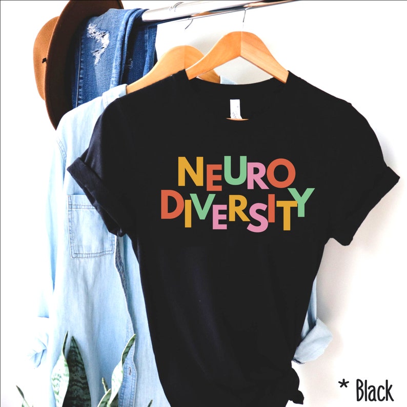 May include: Black t-shirt with the text "NEURODIVERSITY" in colorful letters. The letters are stacked on top of each other and are in different colors, including orange, yellow, green, pink, and blue.