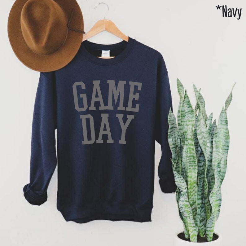 K&ouml;nnte beinhalten: Marineblauer Pullover mit dem Schriftzug "GAME DAY" in grauer Schrift.