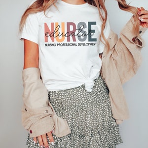 May include: White t-shirt with the text "NURSE educator NURSING PROFESSIONAL DEVELOPMENT" in colorful letters.