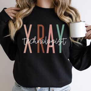 May include: Black sweatshirt with the text "X-RAY technologist" in colourful letters. The letters are in shades of pink, brown, and green.