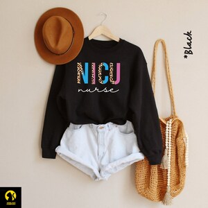 May include: Black sweatshirt with the words "NICU nurse" in colorful letters with a leopard print design.
