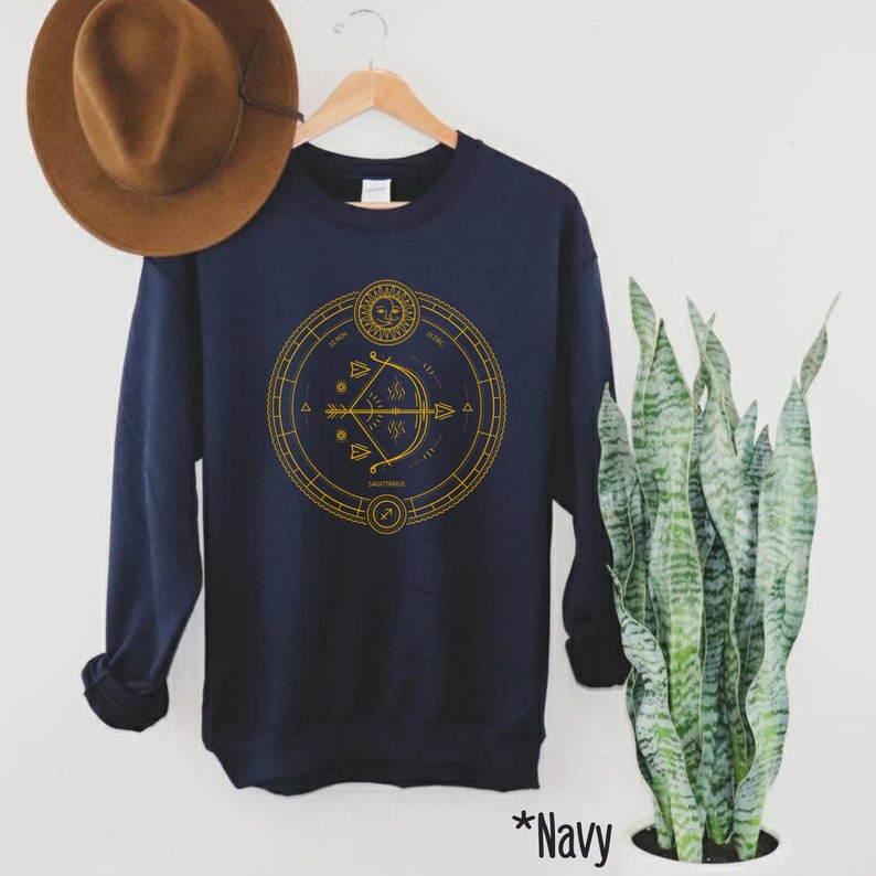 May include: Navy blue sweatshirt with a gold graphic of the Sagittarius zodiac sign, featuring an arrow and a circle with astrological symbols.