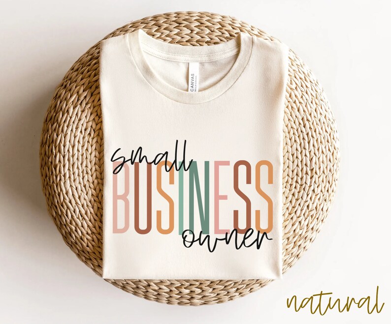 Puede incluir: Una camiseta beige con el texto "small business owner" en letras estilizadas de colores. El texto est&aacute; en un arco&iacute;ris de colores, incluyendo rosa, naranja, marr&oacute;n, verde y azul.