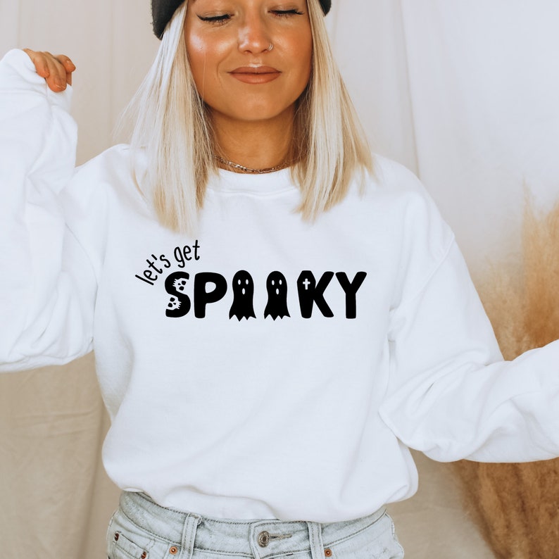May include: White sweatshirt with black text that reads "Let's get spooky" with a ghost and a tombstone graphic.