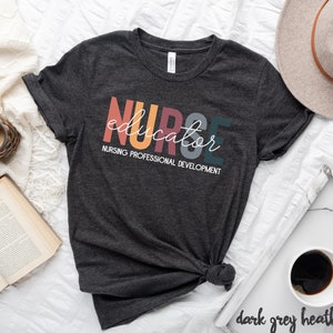 May include: Dark grey heather t-shirt with the text "NURSE educator" in colorful letters and the words "NURSING PROFESSIONAL DEVELOPMENT" in white below.