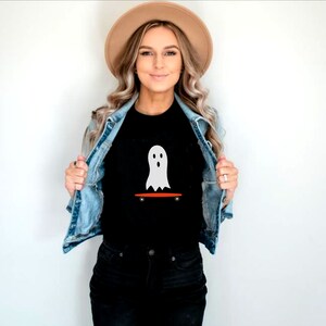 Peut inclure: T-shirt noir avec un motif de fant&ocirc;me blanc sur un skateboard orange. Le fant&ocirc;me a un design simple. Ce t-shirt d&eacute;contract&eacute; est id&eacute;al pour un usage quotidien, notamment pour Halloween ou la saison effrayante.