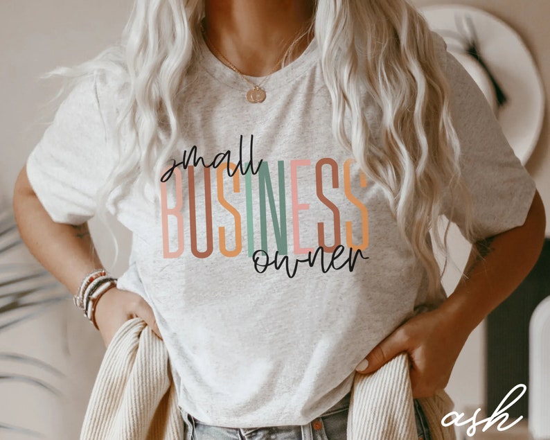 Puede incluir: Una camiseta gris con el texto "small business owner" en letras de colores.